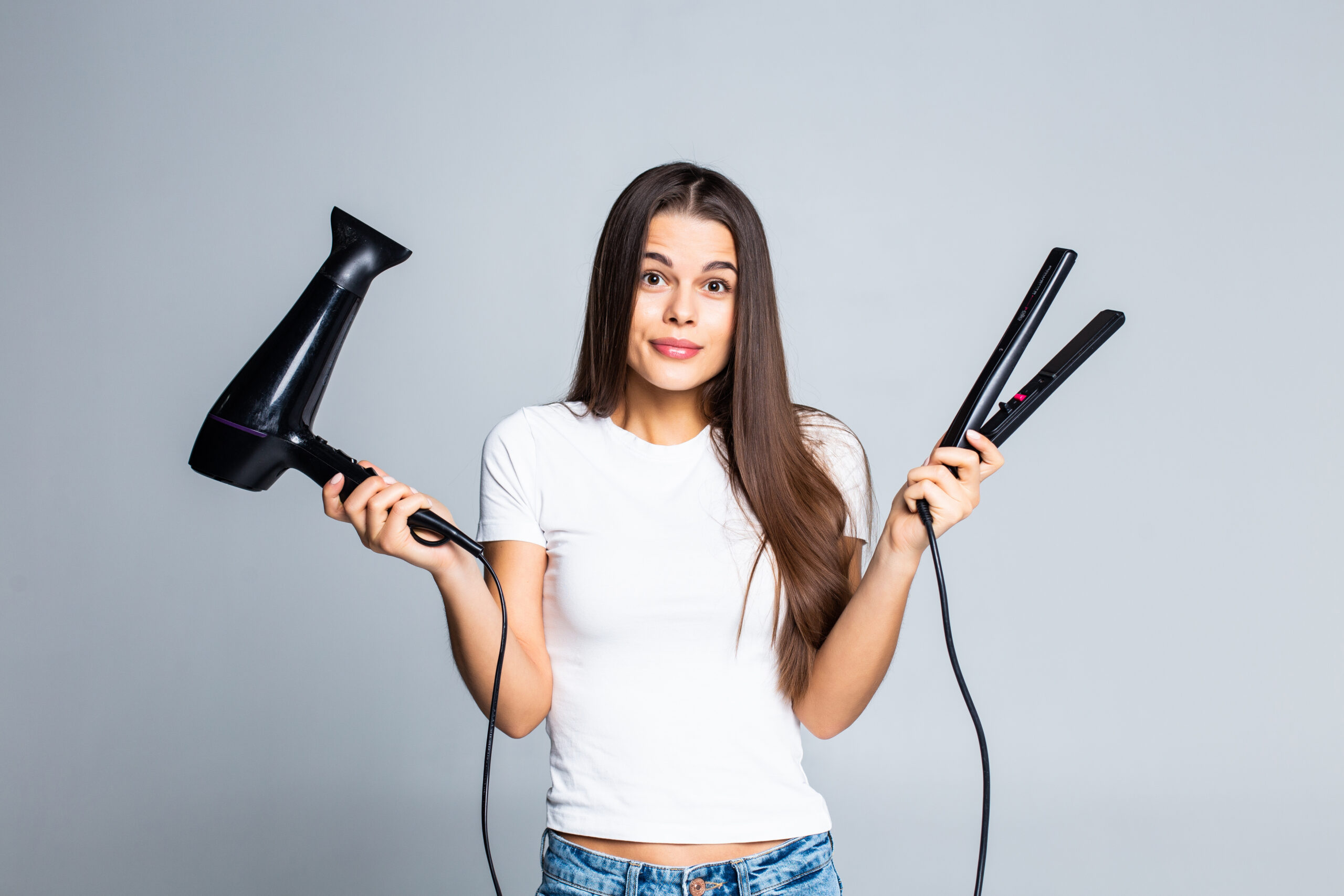 Young pretty woman holding hair dryer and straightening isolated on white background infrared heating element